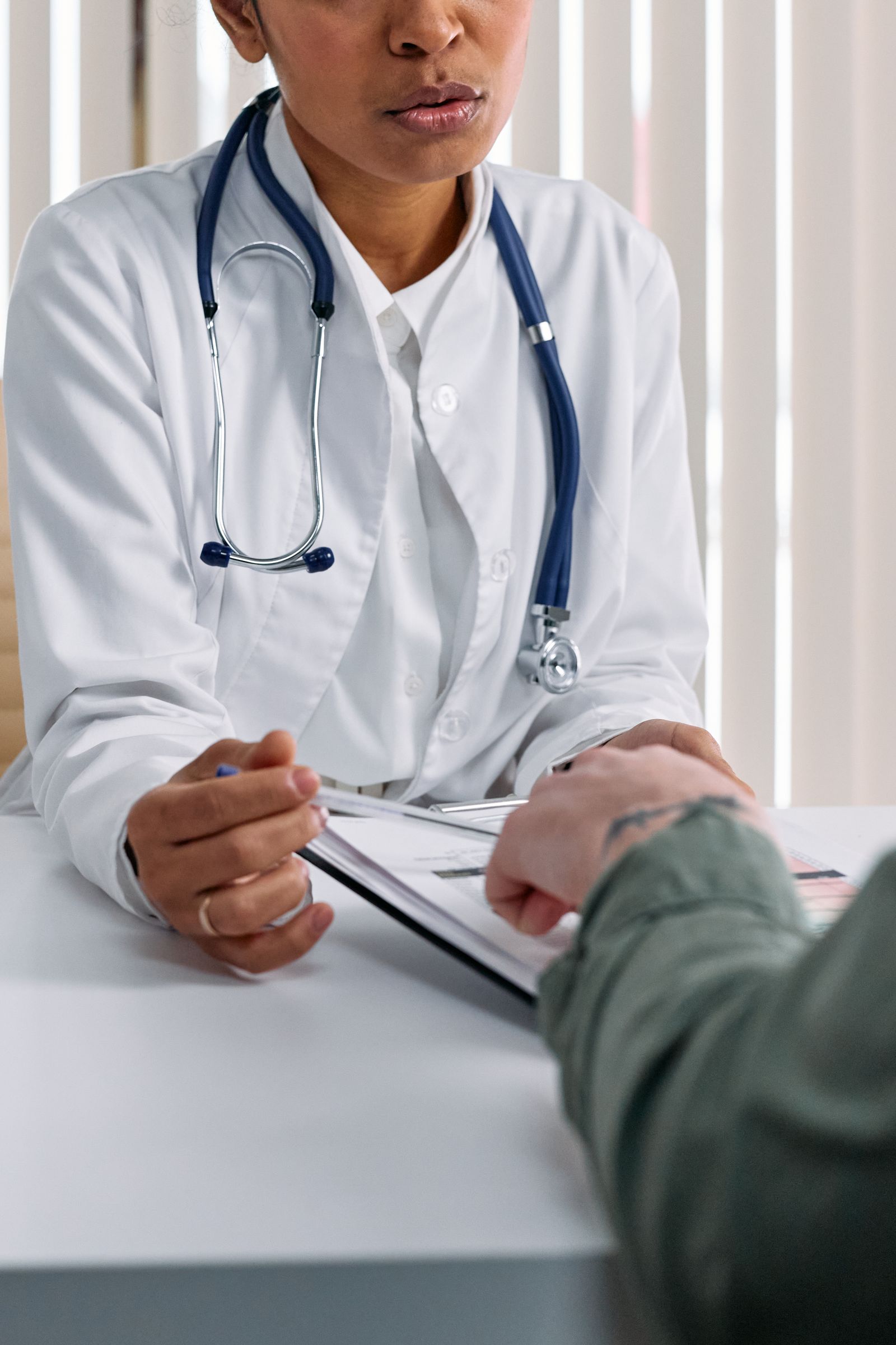 A doctor consulting a patient across a desk in a modern practice office