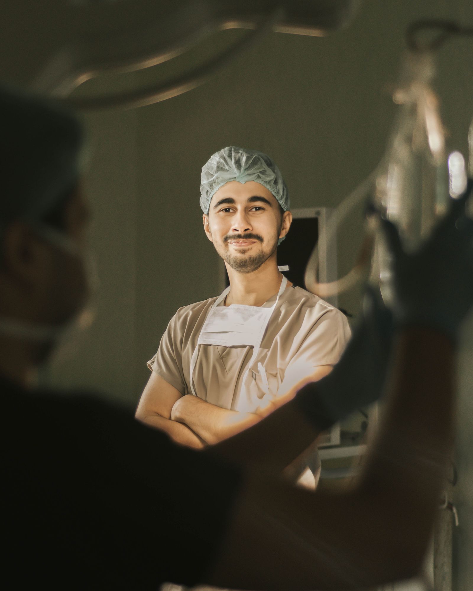A surgeon in scrubs, arms crossed, between cases in the operating suite